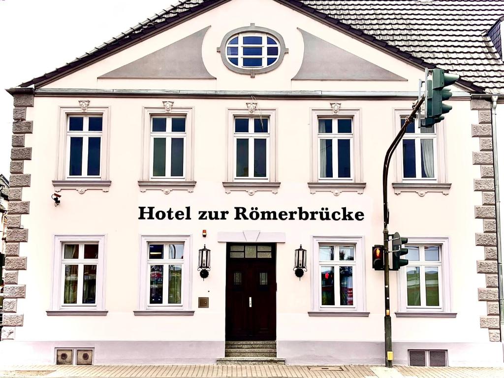 新维德Hotel zur Römerbrücke的白色的建筑,有黑色的门和街道灯