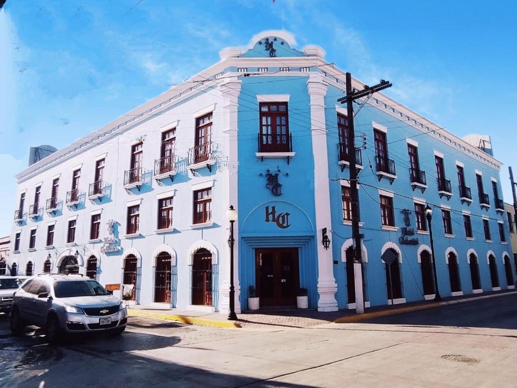 马塔莫罗斯HOTEL COLONIAL MATAMOROS的一座蓝色和白色的建筑,前面有停车位