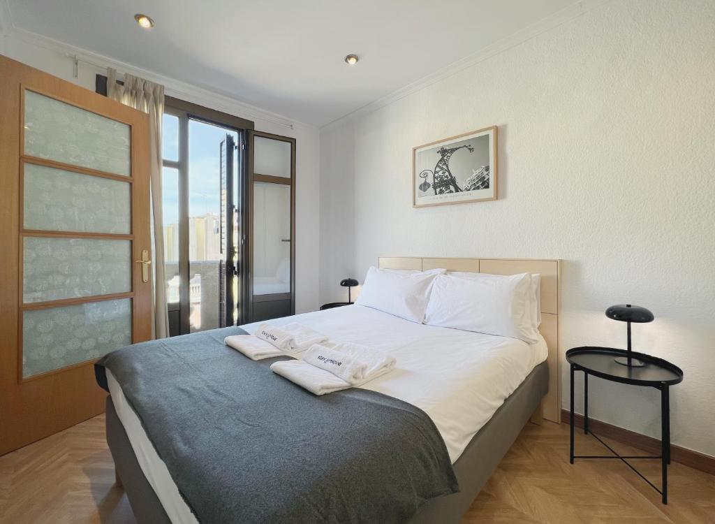 巴塞罗那Stay U-nique Apartments Calabria的卧室配有一张带白色床单和枕头的大床。