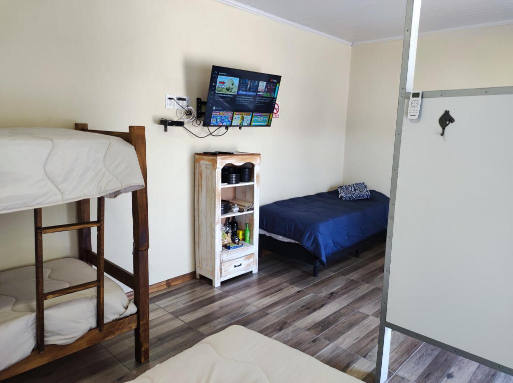 特立尼达岛Casita de Piedra 10的一间卧室配有一张双层床和一张床,配有电视