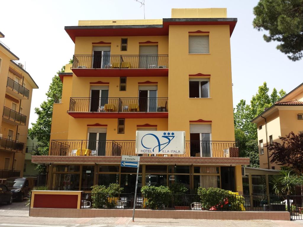 里米尼伊塔拉别墅酒店的黄色的建筑,前面有标志