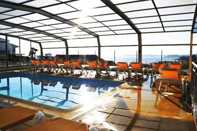 桑亨霍里维洛公寓的一座大型建筑中带橙色椅子的游泳池