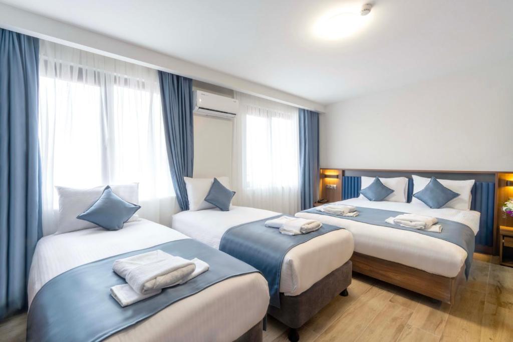 伊斯坦布尔THE BOSFOR HOTEL的酒店客房,配有3张带蓝白色枕头的床