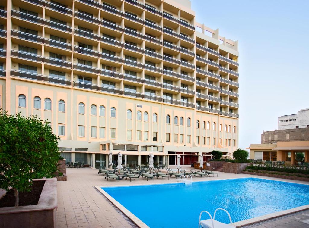 多哈Treffen House Doha - next to Msheireb Metro Station and Souq Waqif的一座大型建筑,前面设有一个大型游泳池