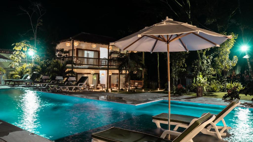 托兰克索Pousada Recanto Caxando的房屋旁的游泳池配有椅子和遮阳伞