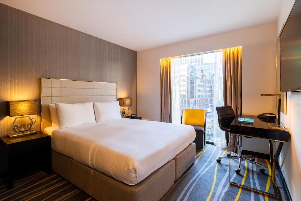 伦敦Hotel Saint London的配有一张床、一张书桌和一扇窗户的酒店客房