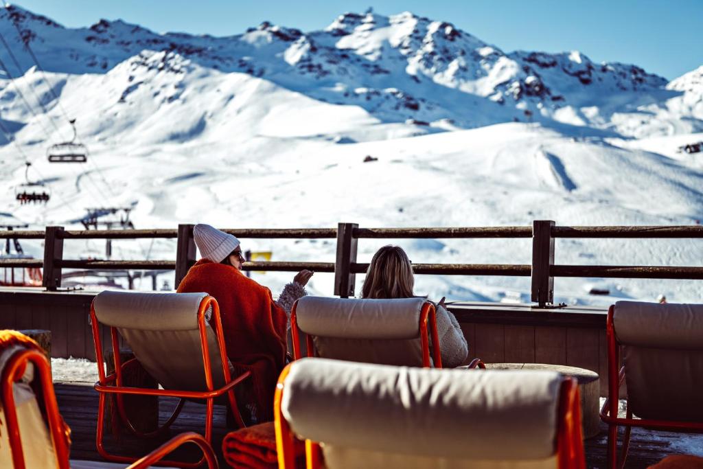 葱仁谷Le Val Thorens, a Beaumier hotel的两人坐在滑雪缆车上,眺望着高山