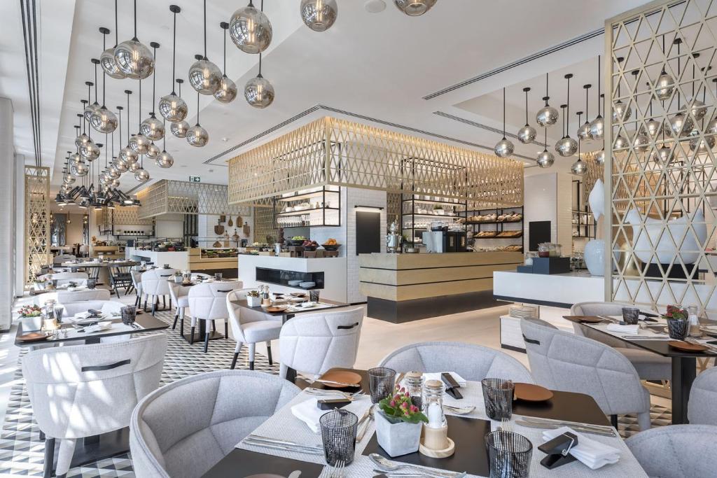 迪拜班达阿炎罗塔纳 - 迪拜河酒店的一间带白色桌椅的餐厅和一间厨房