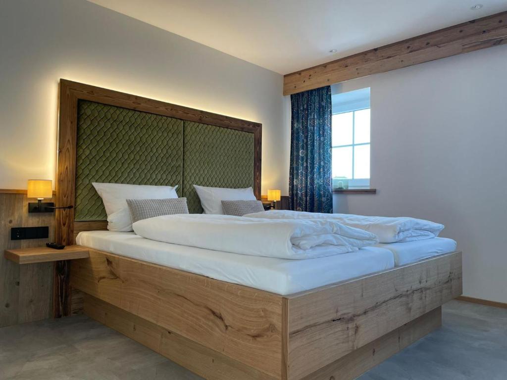 苏尔茨巴赫-罗森贝格Hotel Gasthof zum Wulfen的一间卧室配有一张大床和木制床头板