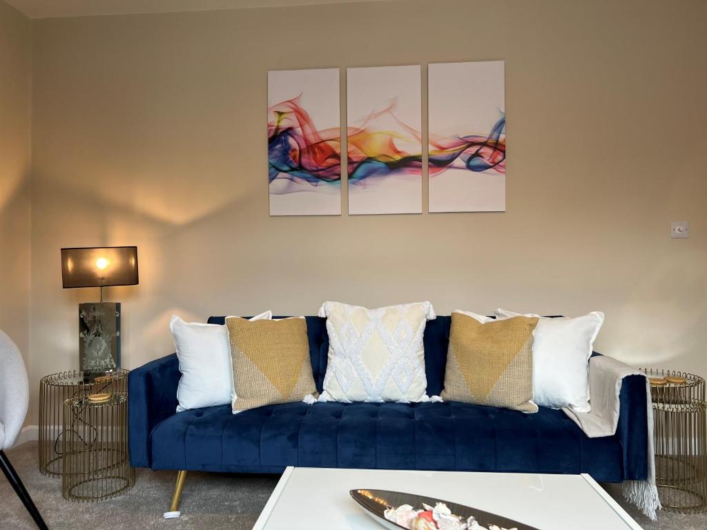 温彻斯特Charming 4-Bed House in Winchester Free Parking的客厅里一张蓝色的沙发,墙上有三幅画