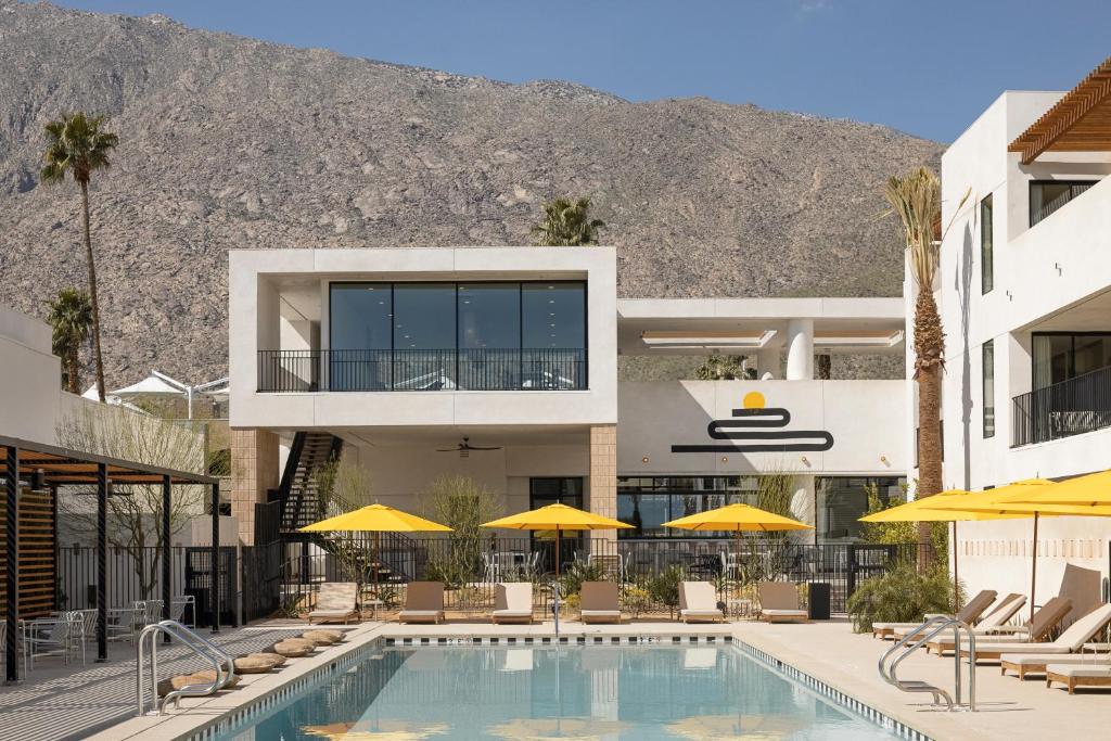 棕榈泉Drift Palm Springs的酒店设有带椅子和遮阳伞的游泳池