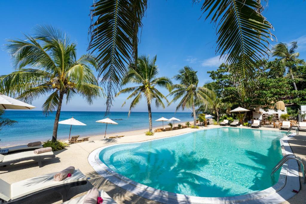 高兰Lanta Palace Beach Resort & Spa - Adult Only的棕榈树和海洋海滩上的游泳池