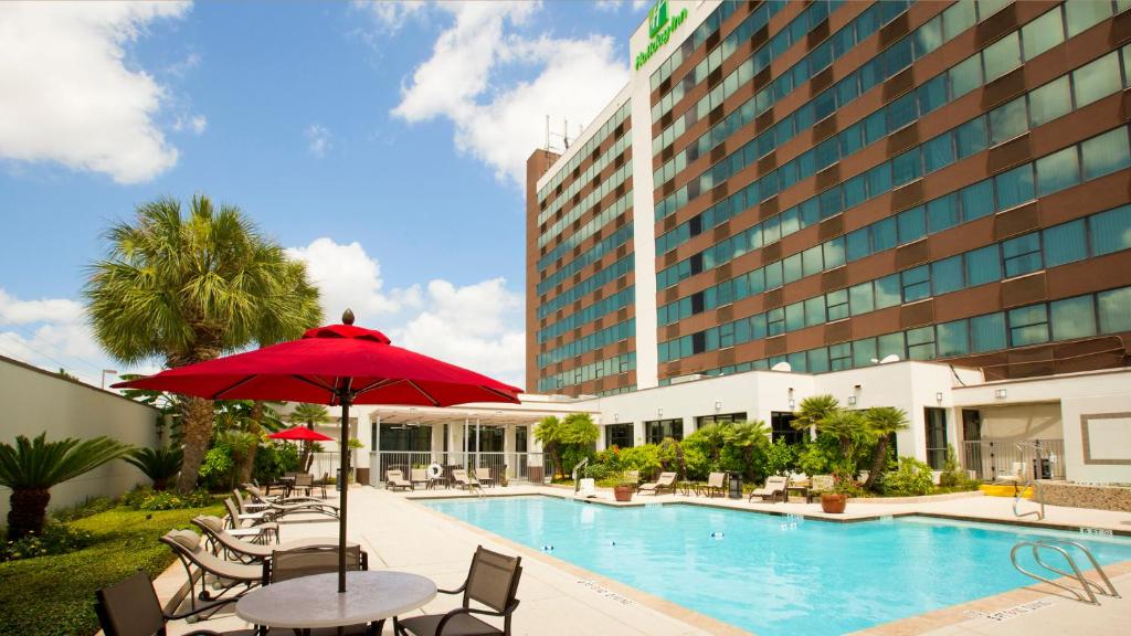 休斯顿休斯顿S-Nrg区-医疗中心假日酒店的酒店设有一个游泳池和一个带遮阳伞的桌子