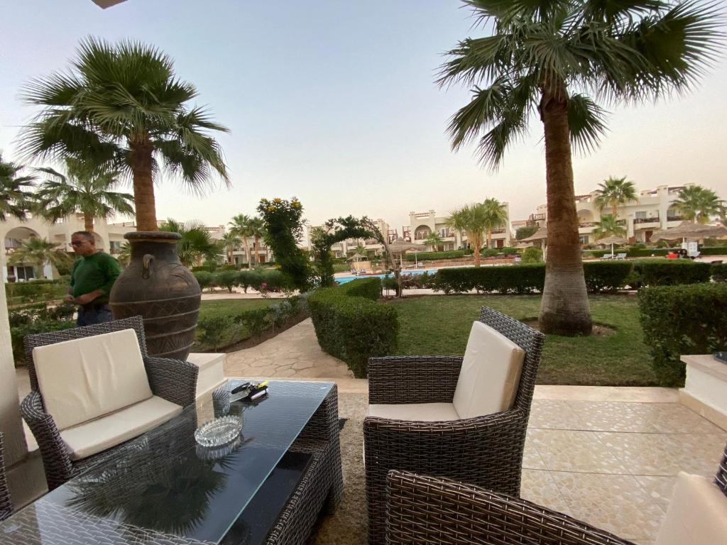 沙姆沙伊赫Renoviertes Luxusapartment Sunny Lakes 1 Sharm El-Sheikh nun auch für Langzeitmieter buchbar的一个带桌椅和棕榈树的庭院