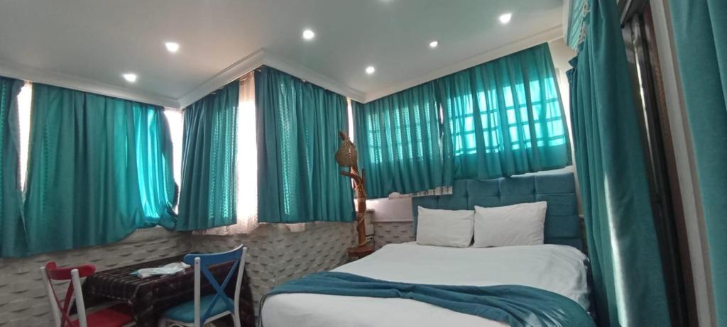 伊兹密尔ŞİRİNYER APART OTEL的一间卧室配有绿色窗帘、一张床和一张桌子