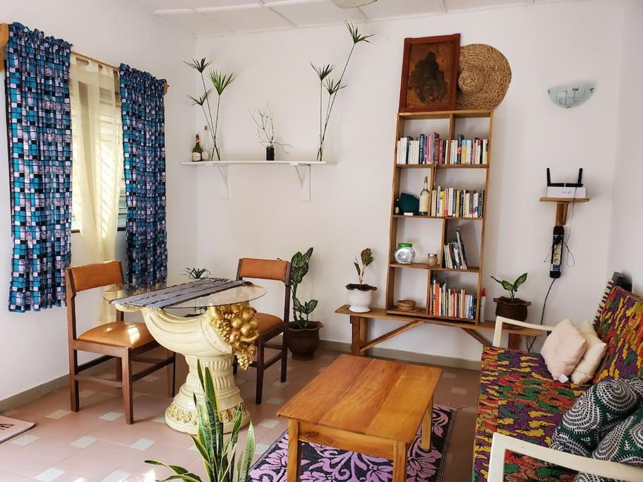 OuidahMaison fleurie Ouidah的客厅配有桌椅和书架