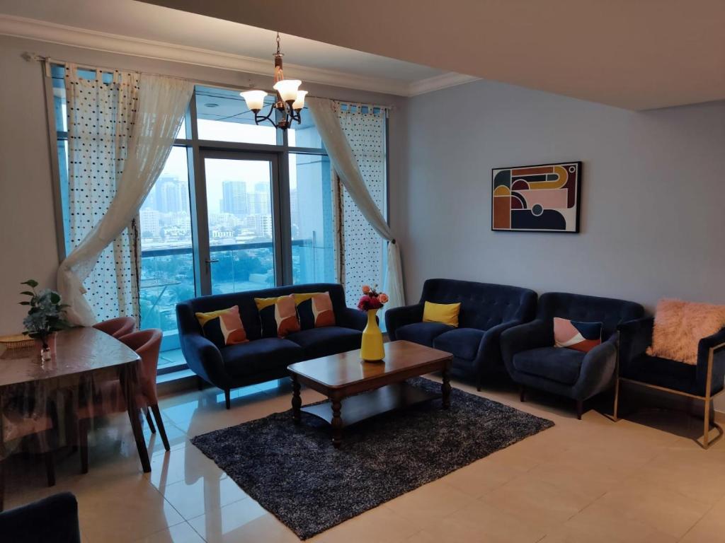 阿吉曼Walk to the Beach, Charming 3-Bedroom Home in Ajman Corniche Residences的客厅配有蓝色的沙发和桌子