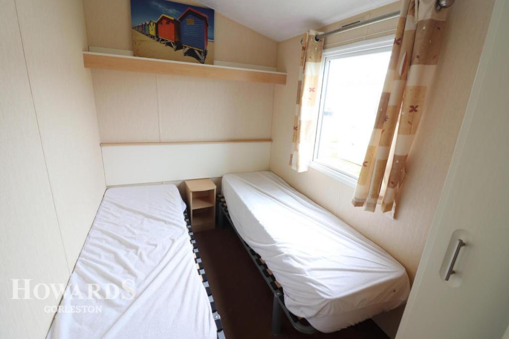 Belton3 bed caravan Norfolk near the coast的小房间设有床和窗户