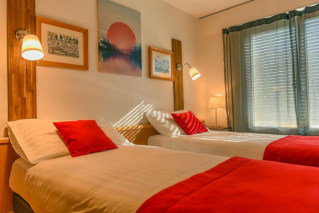 布勒Hotel des Alpes Bulle center的红色和白色的客房内的两张床