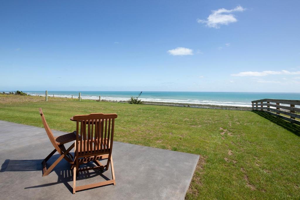 格雷默斯Views over Tasman, New luxury boutique studio overlooking the Tasman Sea的木摇椅,坐在海滩附近的人行道上