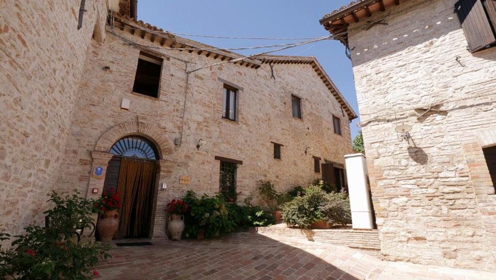 卡梅里诺Borgo de' Varano by Hotel I Duchi的一座古老的石头建筑,在庭院里设有一扇门