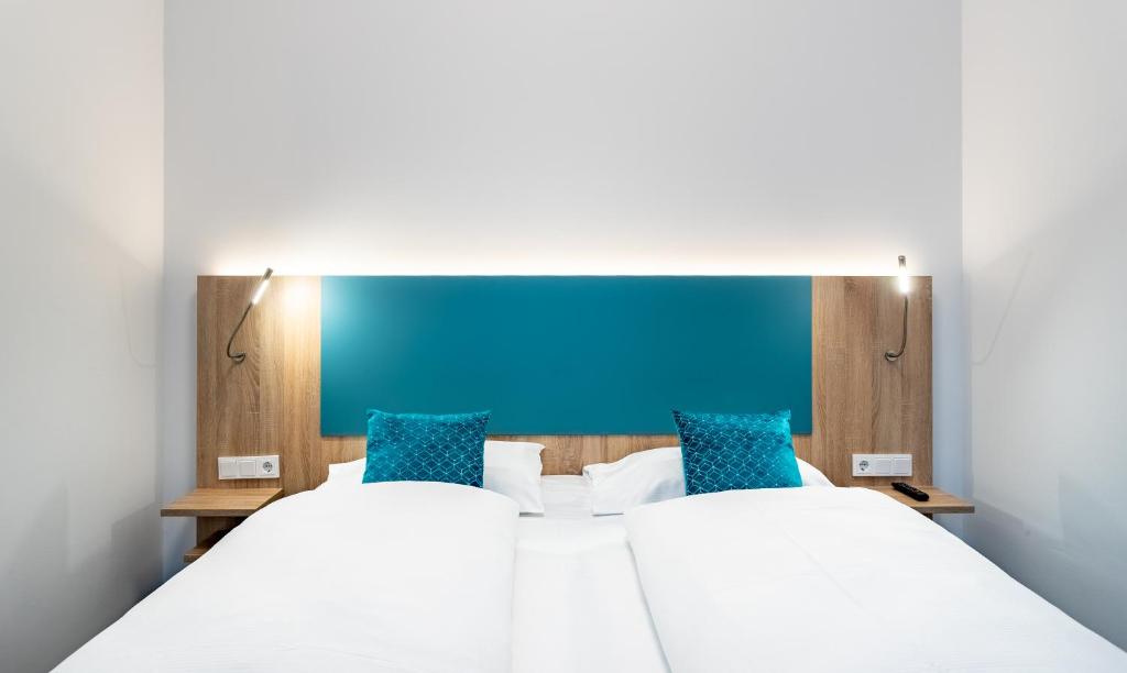 维也纳DaunTown Rooms - Self Check-In的一间卧室设有两张床和蓝色床头板