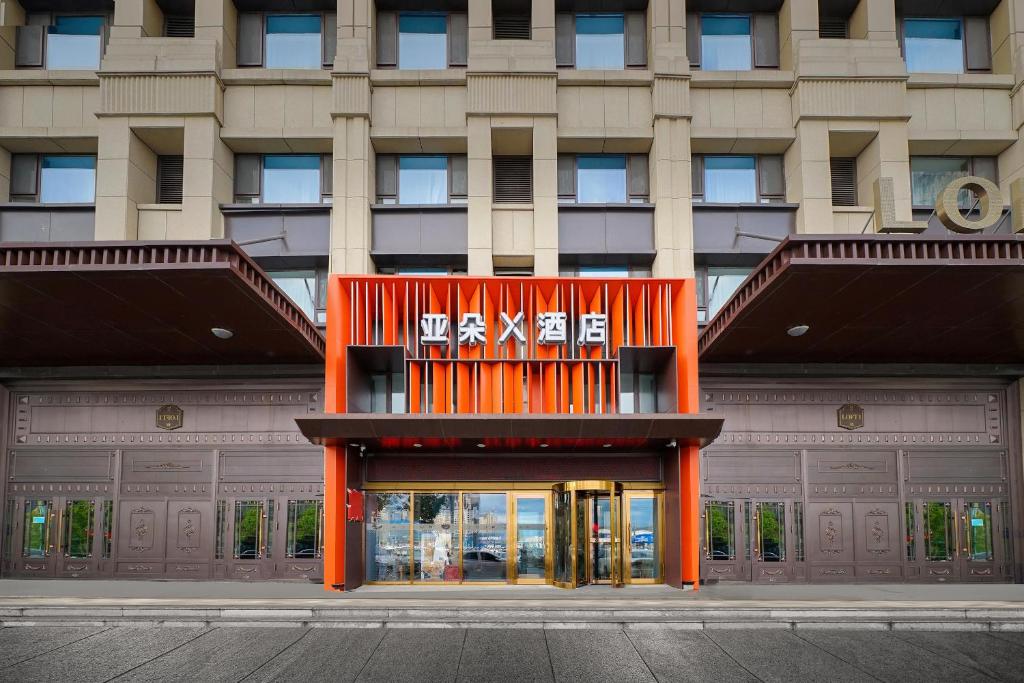 哈尔滨哈尔滨高铁西站亚朵X酒店的一座大型橙色建筑,上面有标志