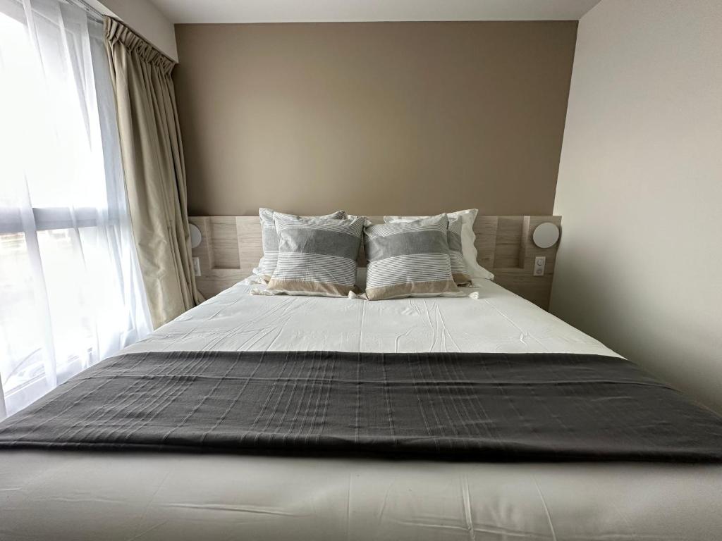 ChaurayHôtel Akena Chauray-Niort的卧室内的一张带白色床单和枕头的床