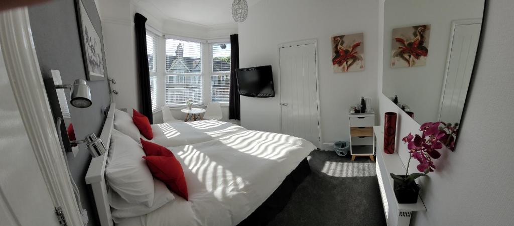 滨海绍森德Edelweiss Guest House的一间卧室配有带白色床单和红色枕头的床。