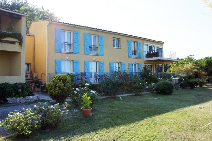 博迪昂Hotel Les Cavalets的一座带蓝色窗户和庭院的大房子