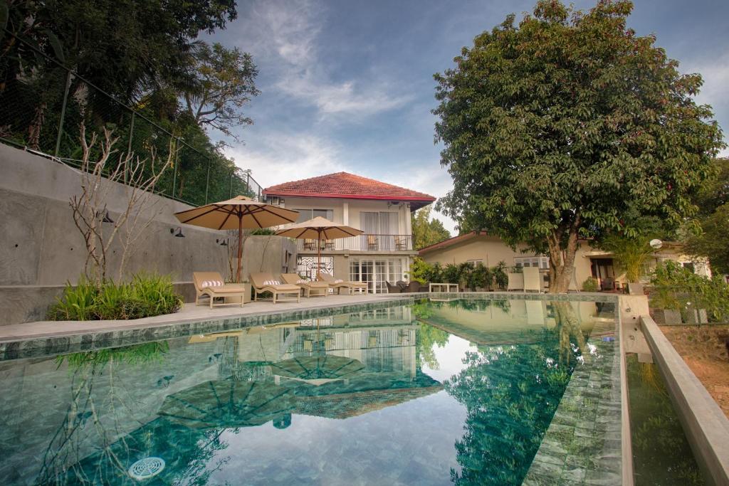 康提Gracian Villa的一个带遮阳伞和房子的游泳池