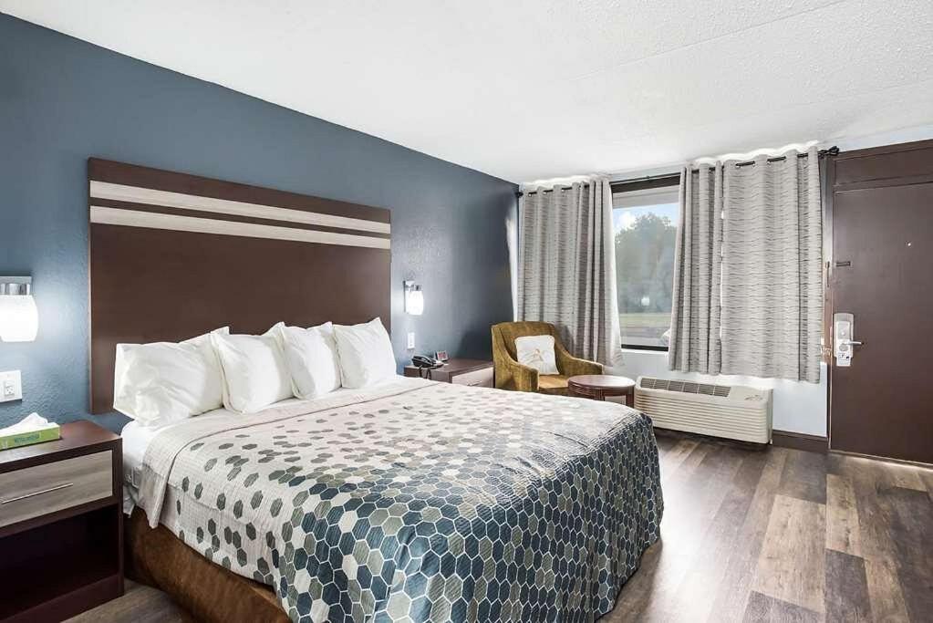 哈蒙顿Red Carpet Inn & Suites NJ-73的配有一张床和一把椅子的酒店客房