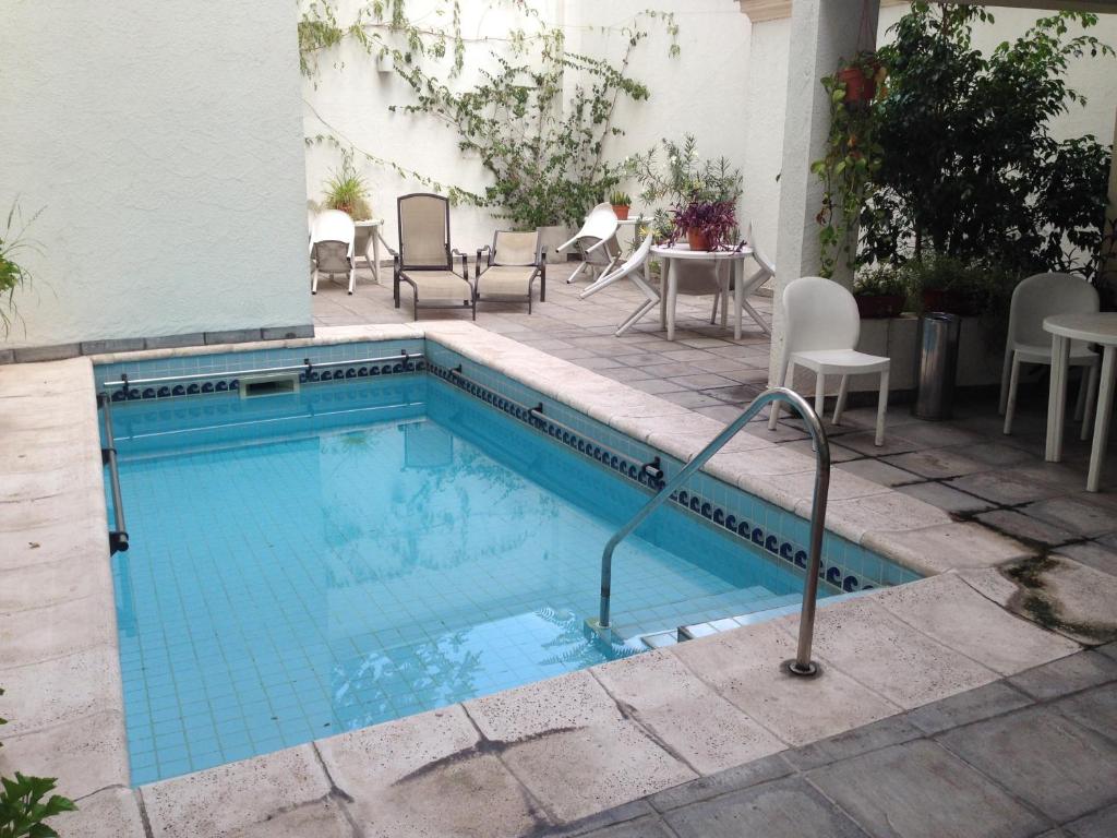 门多萨龚多尔套房公寓酒店的一个带椅子和桌椅的游泳池