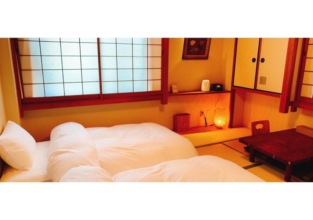 奈良Nara Ryokan - Vacation STAY 49560v的客房设有白色的床、桌子和窗户。