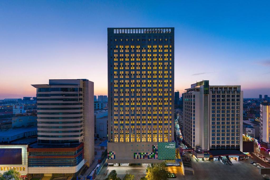 淮安淮安市中心万枫酒店的一座高大的建筑,上面有黄色的灯光