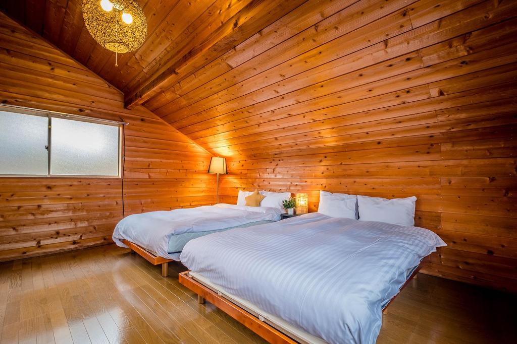 富士河口湖Stella Rental Villa Engawa House的木制客房内的一间卧室配有两张床