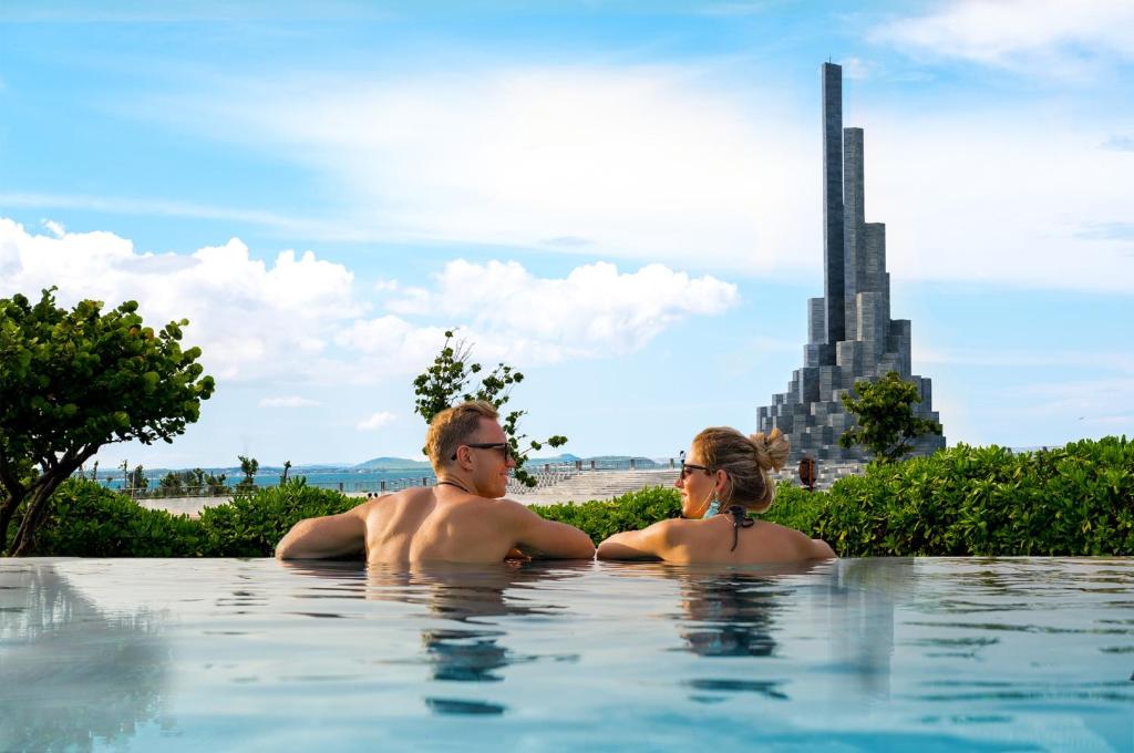 绥和市Stelia Beach Resort的坐在游泳池里的男人和女人
