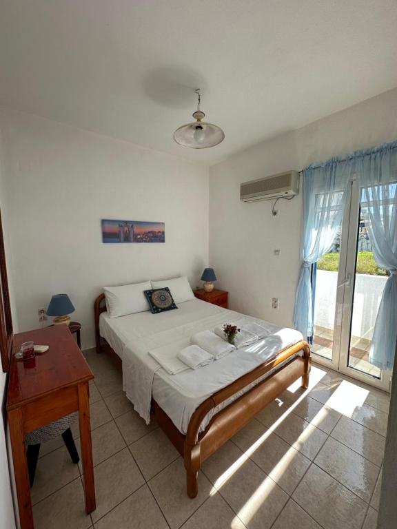 迈加洛丘里2 Ambelia paradise的一间卧室配有一张床、一张桌子和一个窗户。