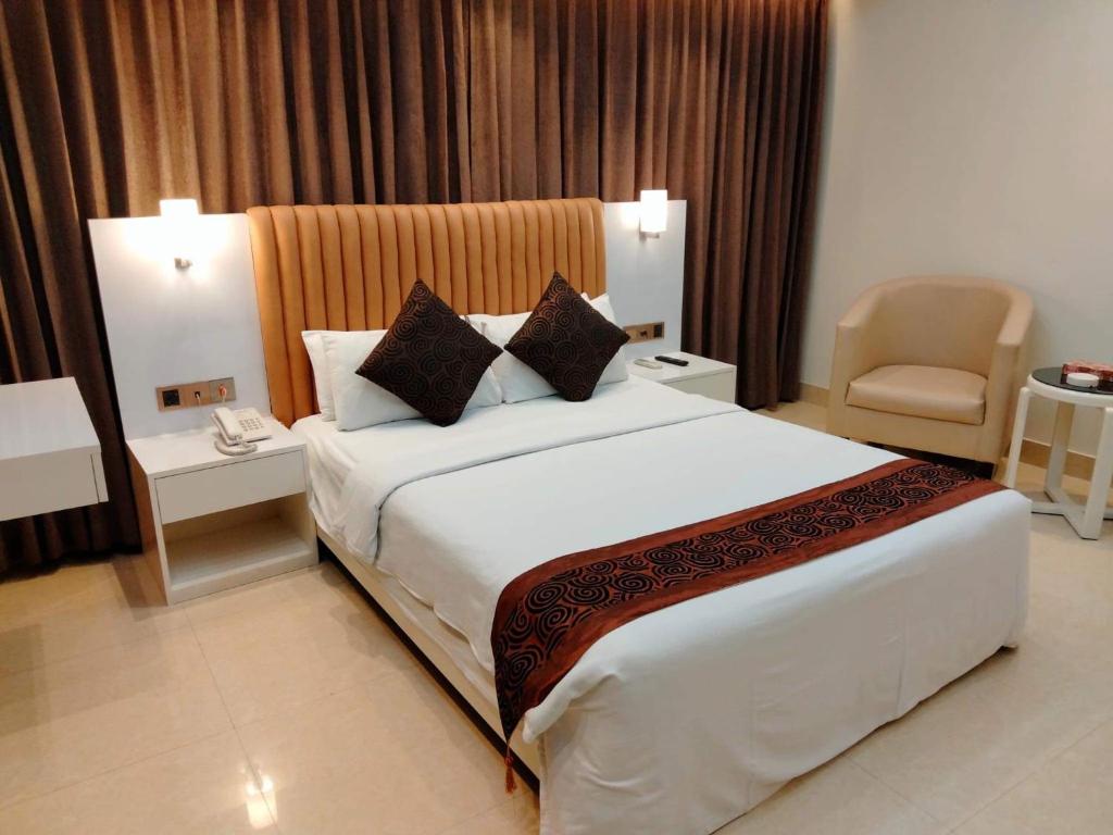 库克斯巴扎白兰花酒店的酒店客房带一张大床和一把椅子