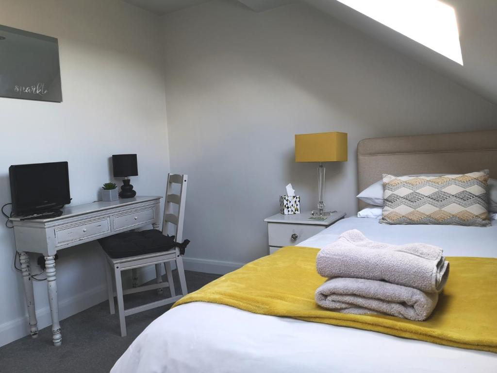 约克York City Homestays的一间卧室配有书桌和一张带毛巾的床。