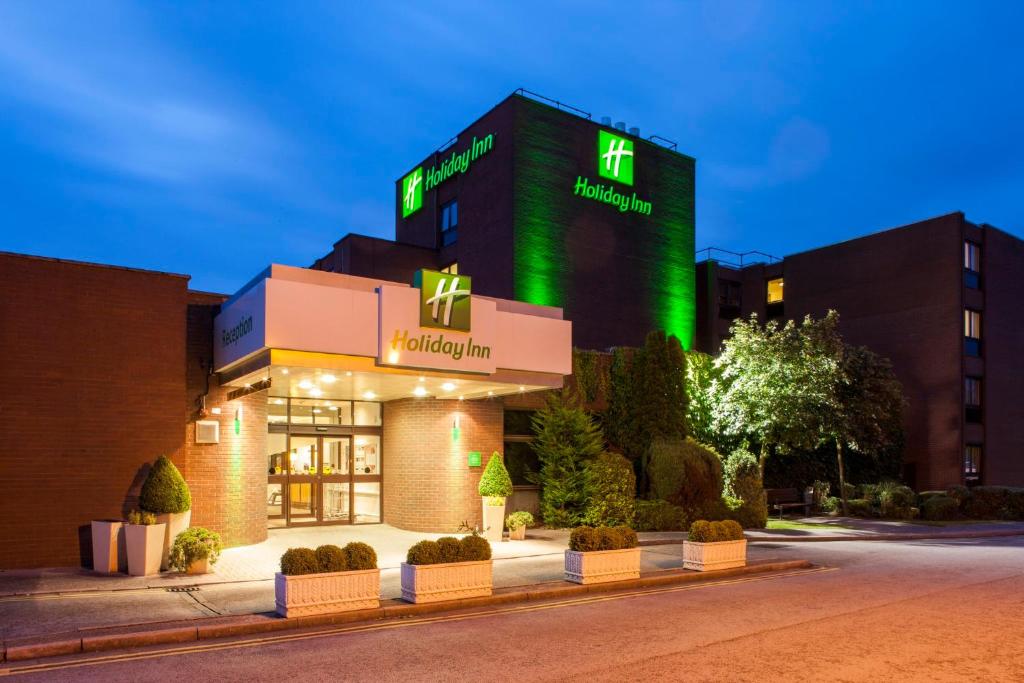 黑多克Holiday Inn Haydock, an IHG Hotel的一座医院建筑,上面有绿色标志