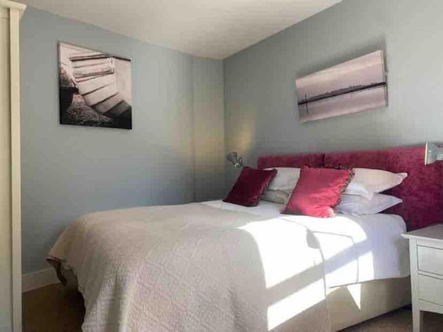 考斯Flat2BeckfordMews的卧室配有带红色枕头的大型白色床