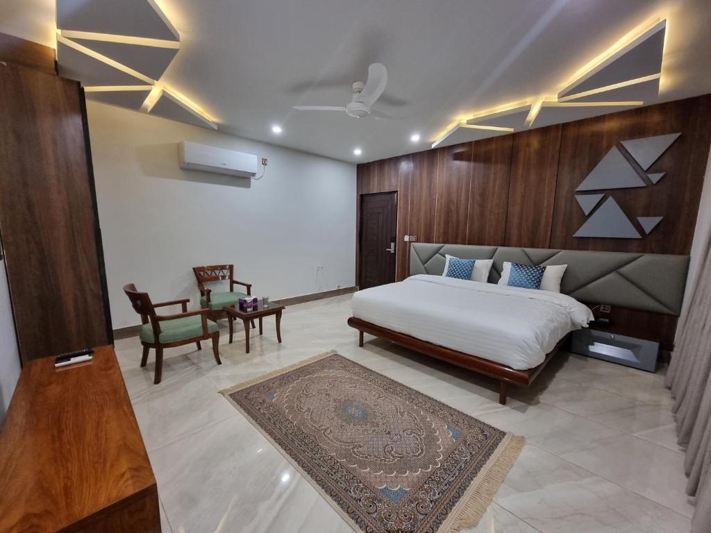 奎达Grand Hotel Quetta的卧室配有1张床、1张桌子和1把椅子