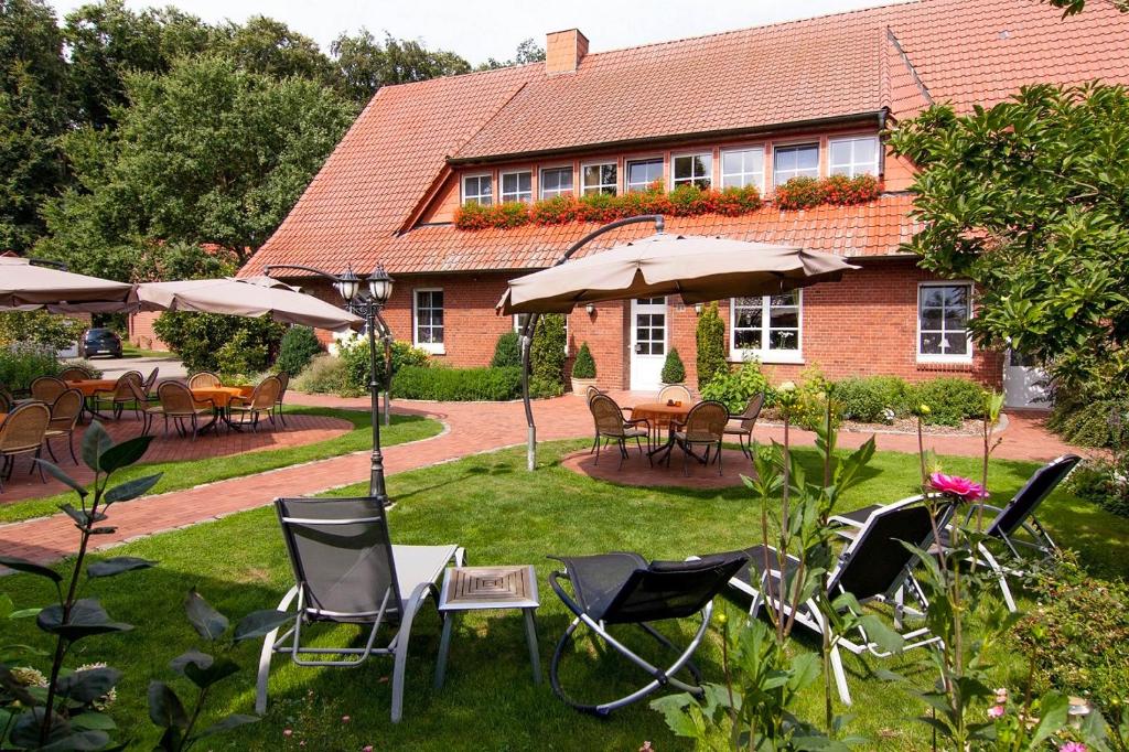 格雷文Ferienhof Große Drieling的房屋前设有带桌椅和遮阳伞的花园