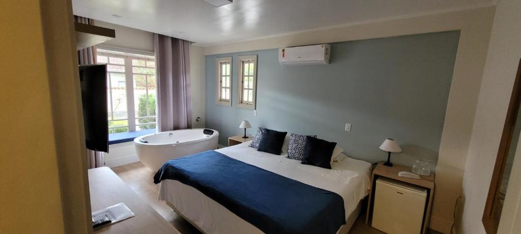 坎波斯杜若尔当杜孔迪旅馆的一间卧室配有一张床、一个浴缸和一台电视。