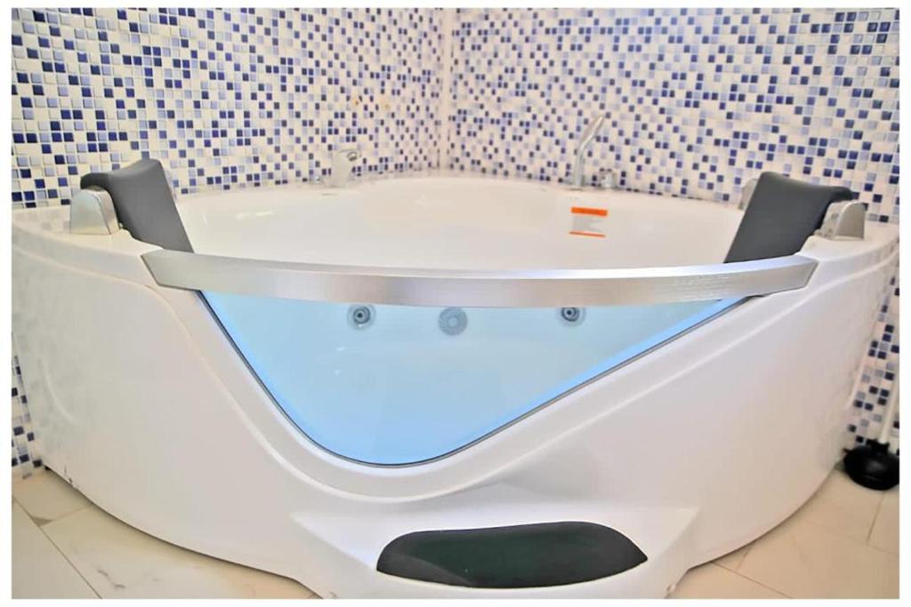 博博迪乌拉Oasis Lawafossi的浴室设有白色浴缸,浴室设有瓷砖墙