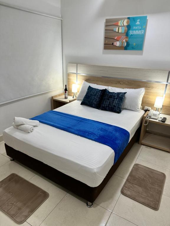 圣玛尔塔Hotel Boutique Deluxe的一间卧室配有一张大床,提供蓝色的床单和枕头