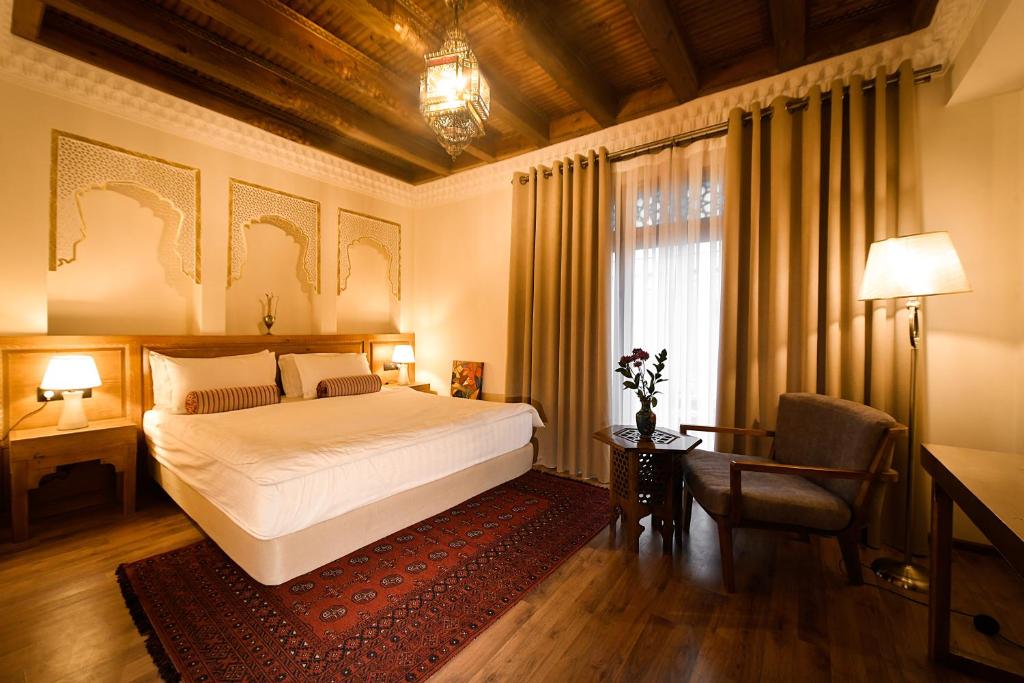 布哈拉库卡尔多什精品酒店 的一间卧室配有一张床、一张书桌和一个窗户。