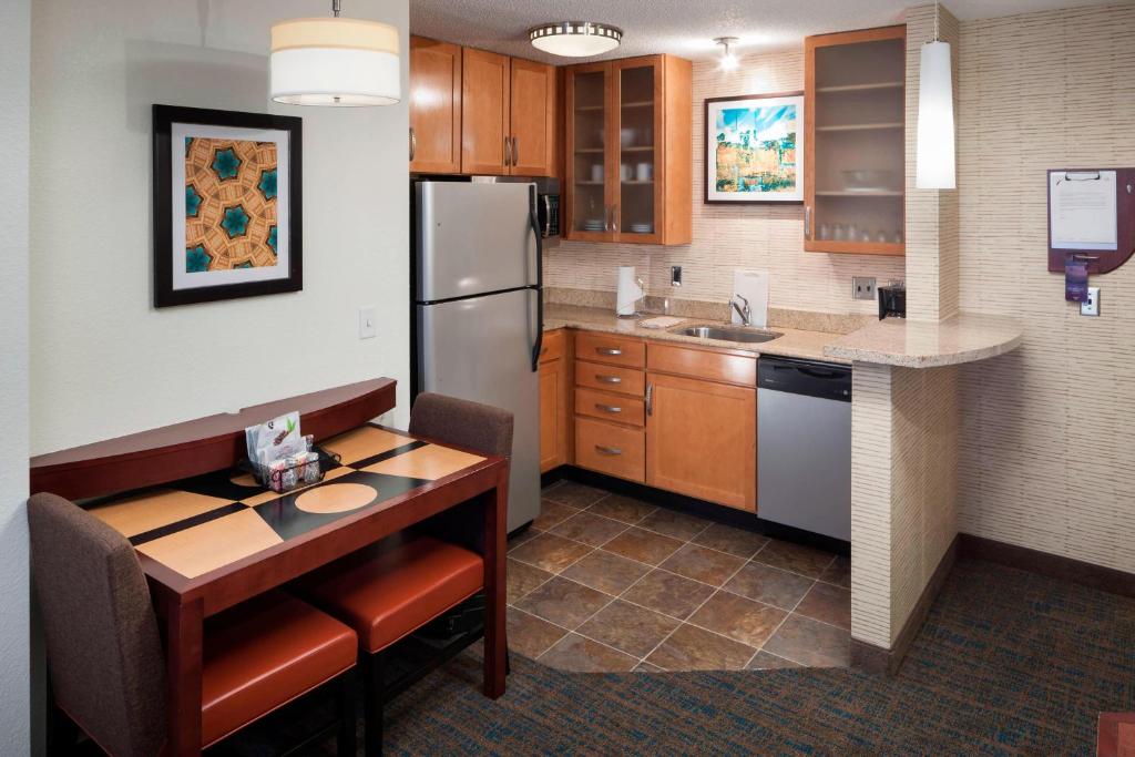 哈蒂斯堡Residence Inn by Marriott Hattiesburg的厨房配有桌子和冰箱