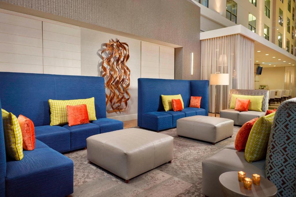 迪凯特亚特兰大迪凯特市中心/埃默里万怡酒店的大堂设有蓝色的沙发和色彩缤纷的枕头。